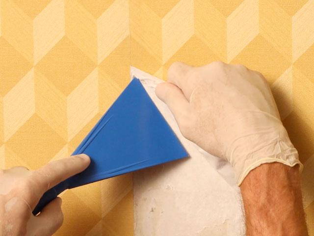 retrait du papier peint avec une spatule et des gants